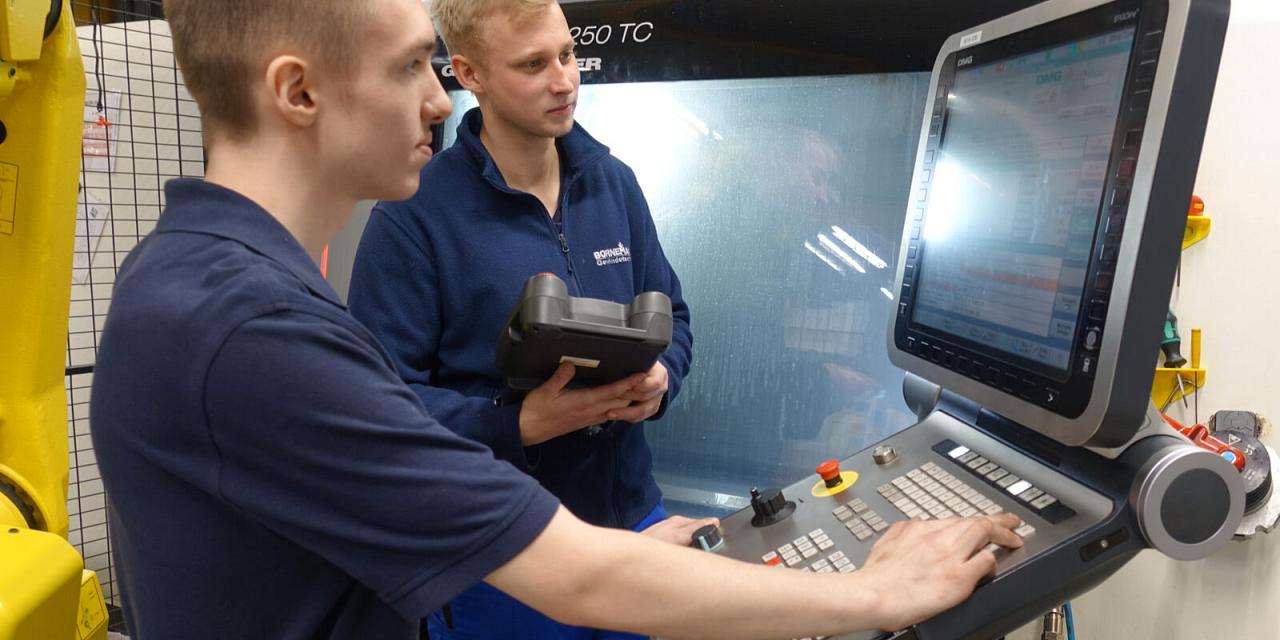 Zwei Auszubildende bedienen eine CNC-Maschine